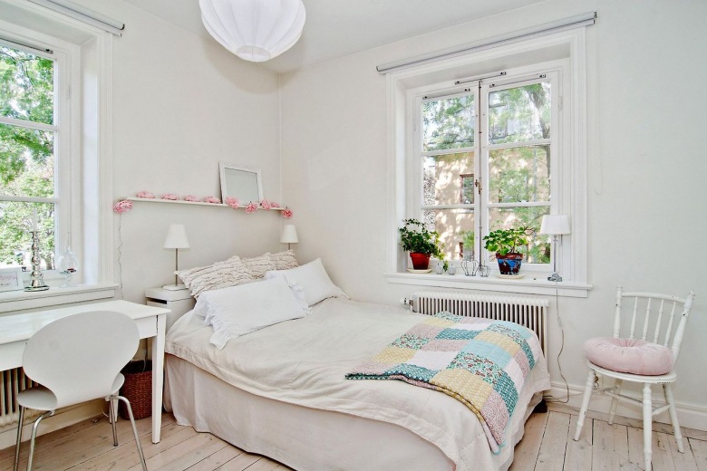 Biała sypialnia z patchworkowa narzuta w pastelach i różową girlandą na małej półce nad łóżkiem (24568)
