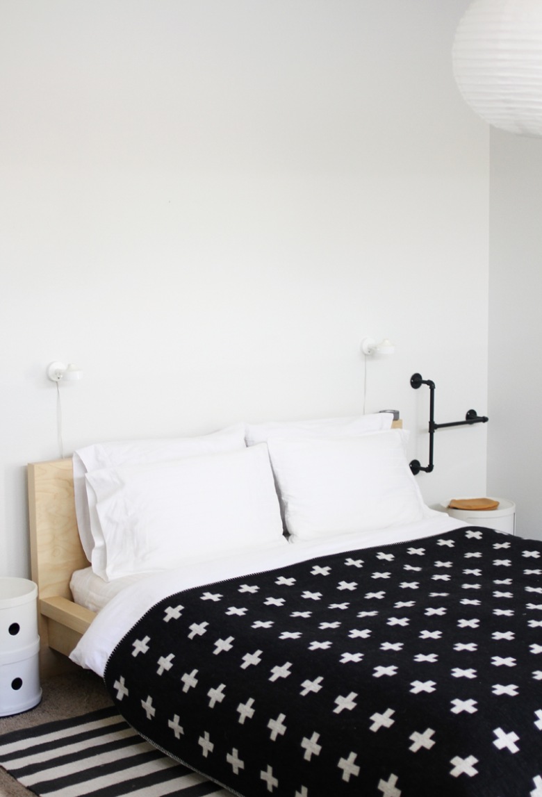 Drewniane łóżko,pasiasty dywan,czarna narzuta w białe gwiazdki (21399)