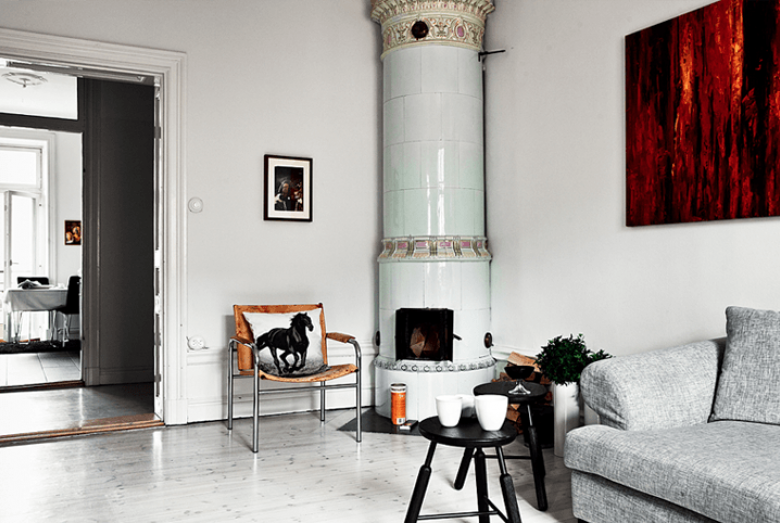 Skandynawski bialy salon z ceramicznym piecem, szarą sofą,i nowoczesnym obraze, w brązach (21081)