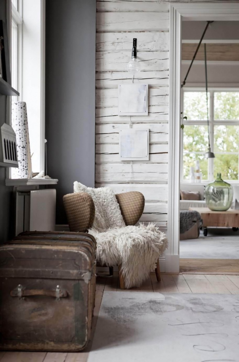Brązowy fotel uszak,szare ściany,białe bielone drewno na scianie,brązowy retro kufer w stylu vintage i biały drukowany dywan (25990)