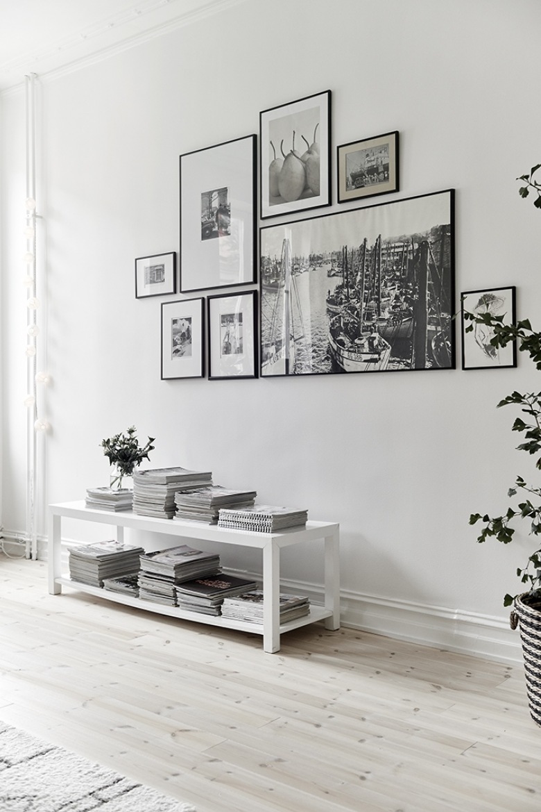 Biała niska konsolka z pólkami w salonie z białymi ścianami,galeria nowoczesnych fotografii w czarnych wąskich ramkach na ścianie (48132)