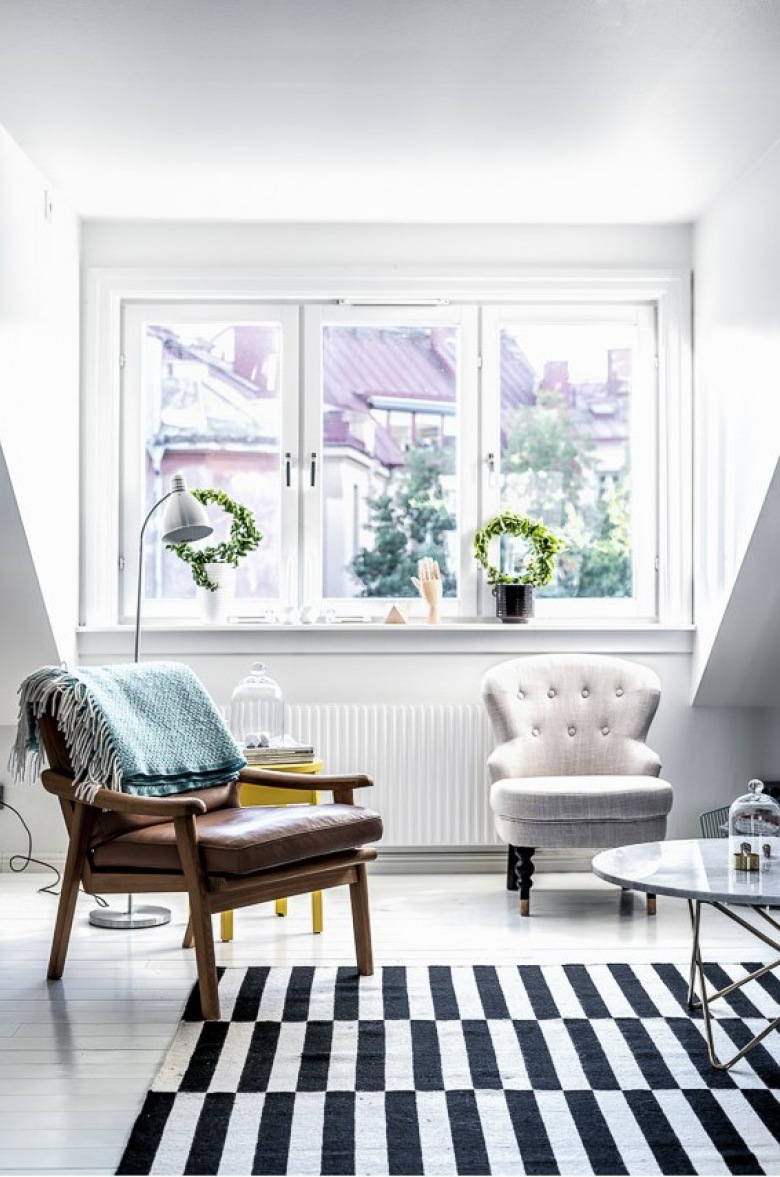 W białym salonie znajdują się meble tworzące eklektyczne zestawienie. Rośliny ustawione na parapecie, o charakterystycznym dla skandynawskich aranżacji okrągłym kształcie, wprowadzają przyjemną naturalną nutę do całego...