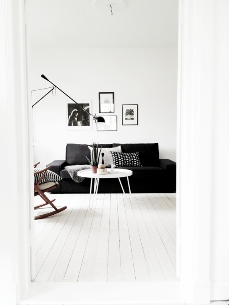 Czarna sofa, czarna lampa podłogowa i czarne ramki z grafikami w białym salonie (20311)