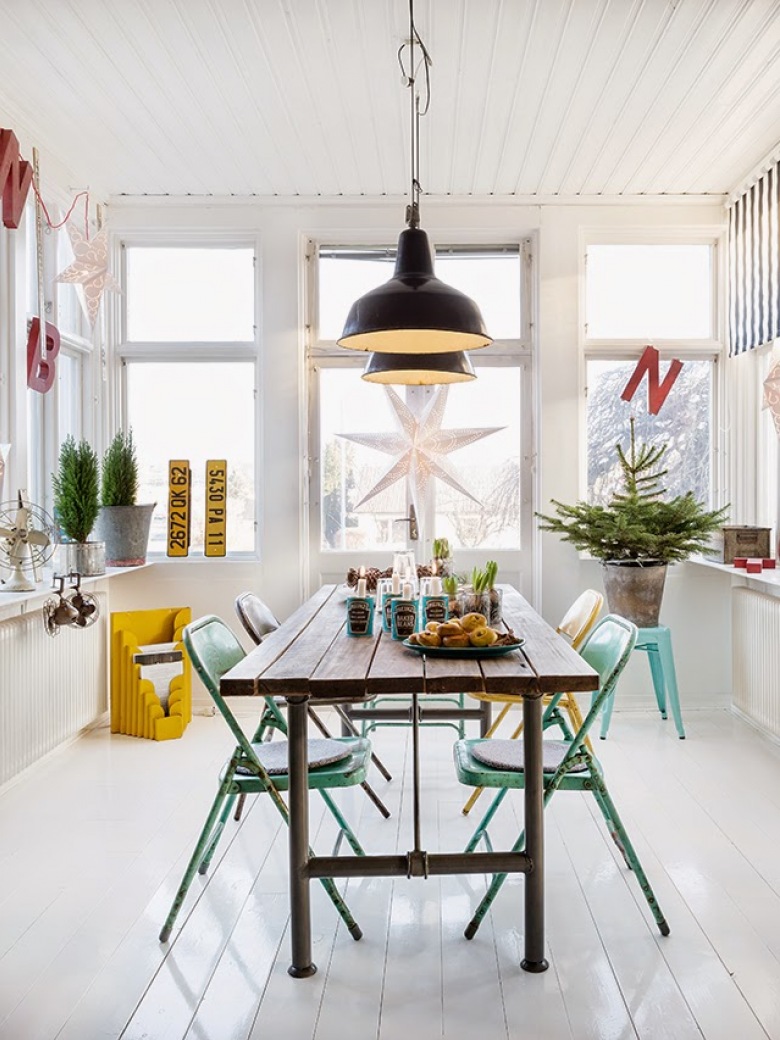 Biała szwedzka jadalnia z czarnymi industrialnymi lampami nad metalowym stołem z drewnianym blatem, turkusowe metalowe krzesła i żółte dodatki w dekoracji białego wnętrza (27524)