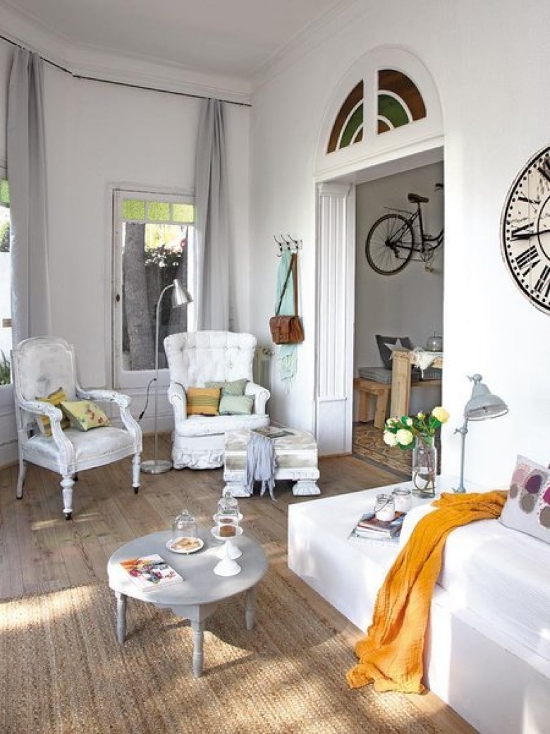 Szare zasłony,białe stylowe fotele,drzwi ze świetlikami,okrągły szary stolik kawowy i duży rustykalny zegar na białej ścianie (26433)