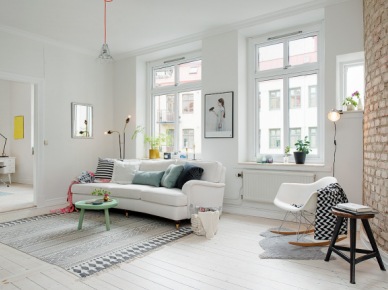 Biała sofa na kółkach,turkusowy stolik pomocniczy kawowy,turkusowe i biało-czarne poduszki,biały fotel na płozach i ściana z czerwonej cegły w salonie,lampa ma czerwonym kablu, (26462)