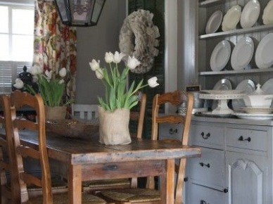 Wiejski rustykalny stół z drewnianymi krzesłami w aranzacji szarej kuchni z wyeksponowanymi talerzami na półkach ściennych (25627)