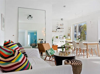 Otwarty salon z dużym lustrem na ścianie i kolorowymi poduszkami w paski na sofie (23402)