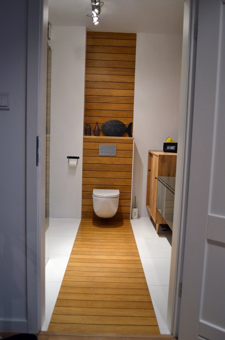 Niezwykle ciekawe rozwiązanie w łazience, gdzie wydzielono drewniany pas od podłogi aż po ścianę. Intrygujący pomysł...