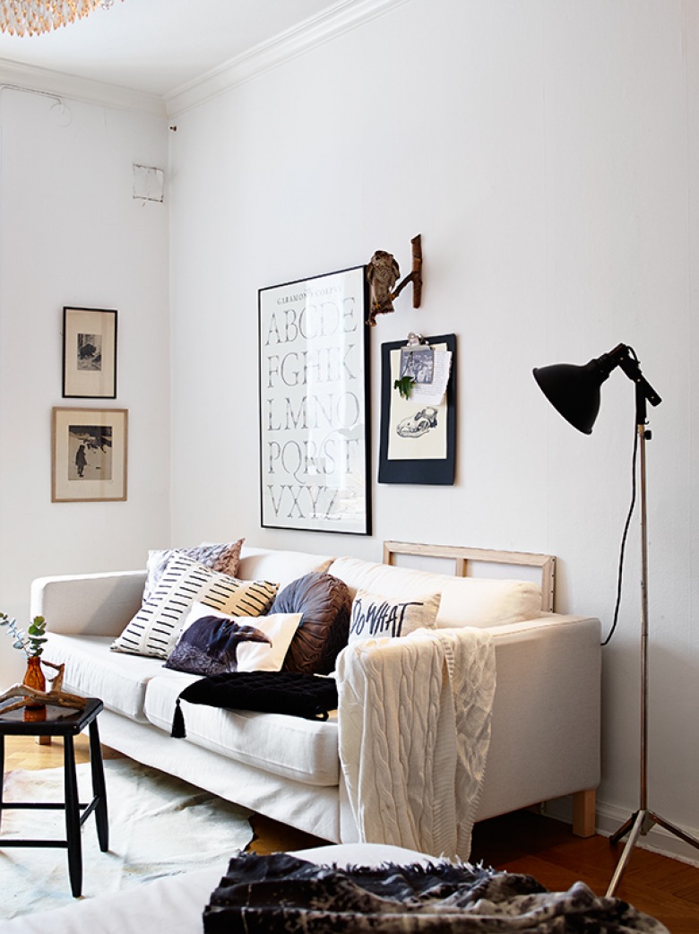 Biała sofa,czarna lampa podłogowa,mały stolik kawowy i grafiki (21473)