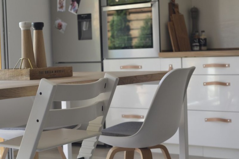 Białe krzesła przy drewnianym stole potęgują wrażenie przytulności i domowego ciepła. Otwarta kuchnia harmonijnie współgra z naturalnym wystrojem...