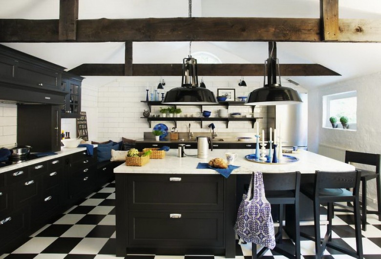 bardzo oryginalna kuchnia - czarne meble kuchenne wspaniale prezentują się na tle białych ścian i czarno-białej posadzce, ułożonej w karo. Niebieskie, ciemne dodatki dodają wnętrzu ekspresji i kolorytu. Ciekawa i piękna kuchnia, na dodatek...