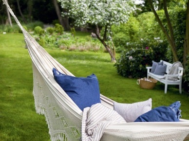 Romantyczny hamak z niebieskimi poduszkami w zielonym ogrodzie (23640)