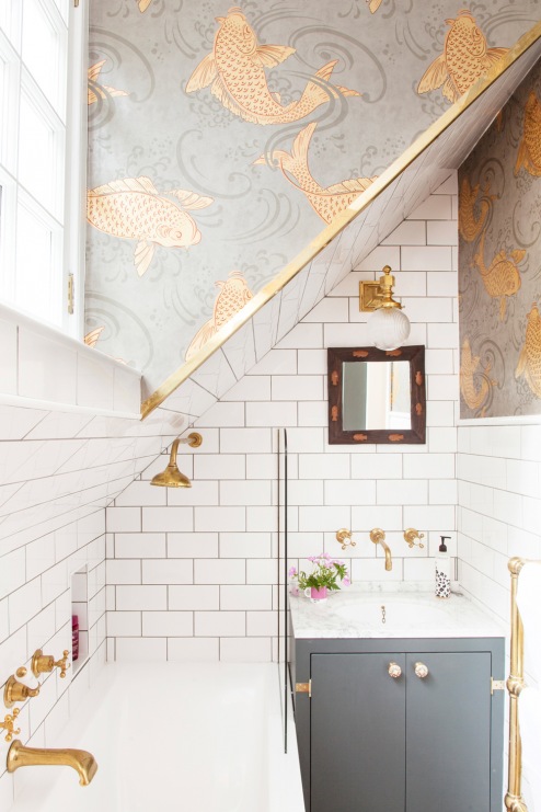 W aranżacji łazienki na szczególną uwagę zasługują także wzorzyste motywy na ścianie. Tapeta ze złotymi rybami...