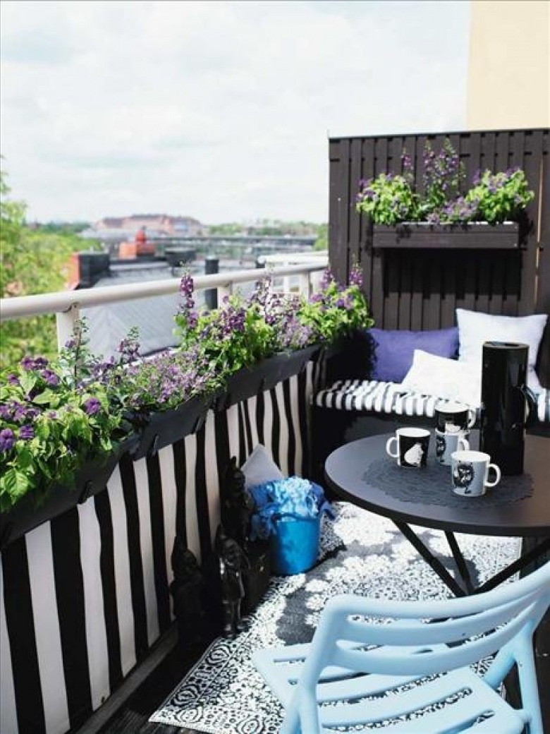 Czarna balustrada na balkonie z wiszącymi fioletowymi kwiatami,aranzacja balkonu w turkusowo-czarnych kolorach,czarny okragły stolik na balkon,czarne meble z metalu na małym balkonie,aranzacja małego balkonu,siedziska z poduchami na małym balkon (37022)