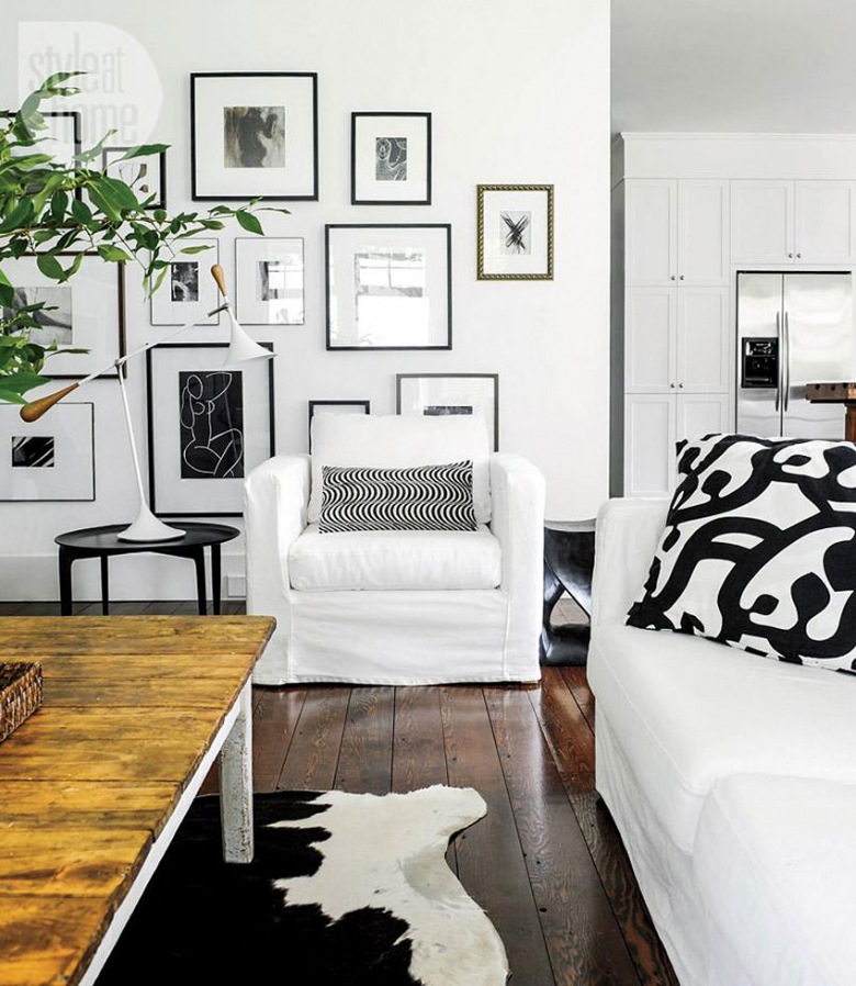 Galeria biało-czarnej fotogreafi i grafik na białej ścianie w salonie z białymi fotelami i sofą i rustykalnym stołem z drewnianym blatem (26785)