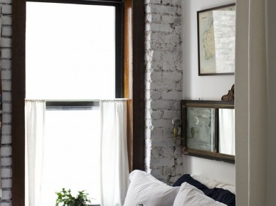 Biała cegła, kryształowy żyrandol i ciemne drewniany ramy okien w sypialni (22968)