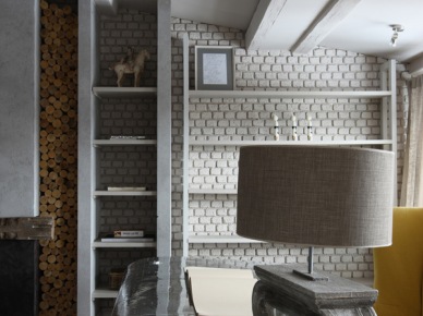 Ściana z białej cegły z półkami,wnęką na drewno kominkowe, francuska lampa vintage i industrialny stolik (27059)