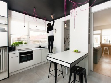 Białe meble , różowe kable z żarówkami i czarny sufit i ściany nad szafkami kuchennymi (22281)