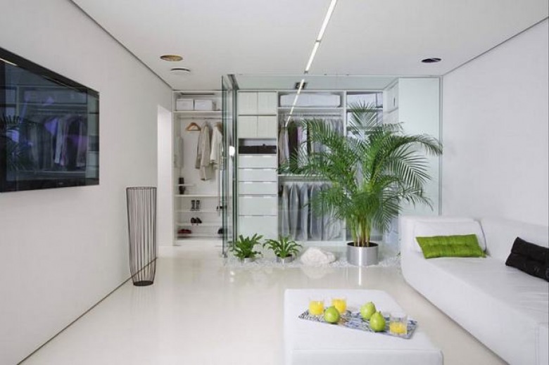 bardzo ciekawy pomysł na aranżację otwartej zabudowy w mieszkaniu - to minimalistyczna dekoracja, gdzie posłużono się bielą i szkłem. Warto zwrócić uwagę na ścianę ze szkła, która łączy i zarazem dzieli salon z garderobą. Znaczącą rolę odegrały tu piękne, zielone rośliny, które utworzone na wzór rabaty, zostały wypełnione białymi...