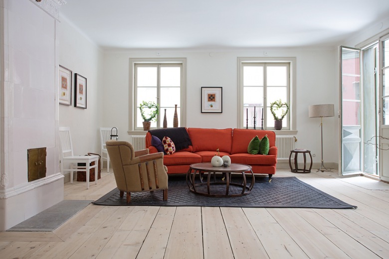 Zdjęcie salonu w stylu skandynawskim z fajną czerwoną sofa, która dodaje kontrastu.