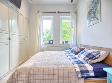 Mała sypialnia z dużym łóżkiem i białą szafą wnękową na całą szerokość ściany (48984)