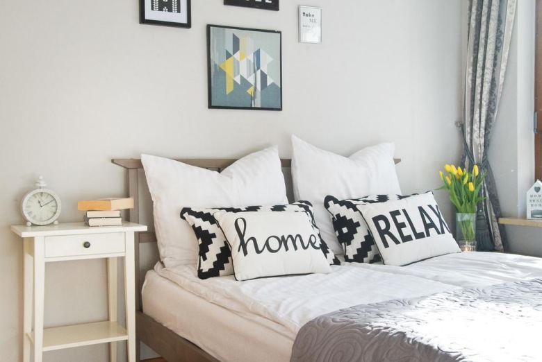 Na łóżku zastosowano wdzięczne ozdoby, jak np. poduszki z typografią nastrajającą do wypoczynku i podkreślającą domową...