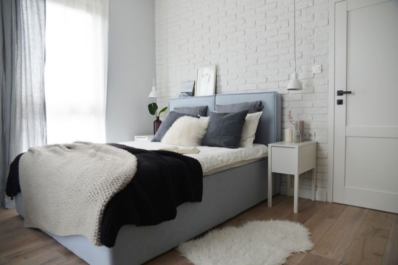 Spokojna aranżacja sypialni ma w sobie wiele ciekawych elementów. Wystarczy spojrzeć na ścianę za łóżkiem. Wyłożono ją...