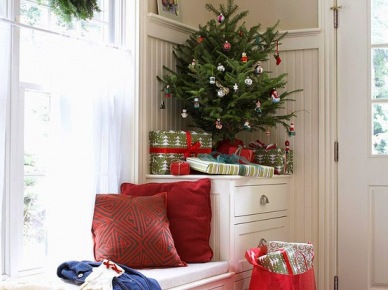 Białe siedziska przy oknie w korytarzu, zielona mała choinka z bombkami i czerwone poduszki dekoracyjne (27332)