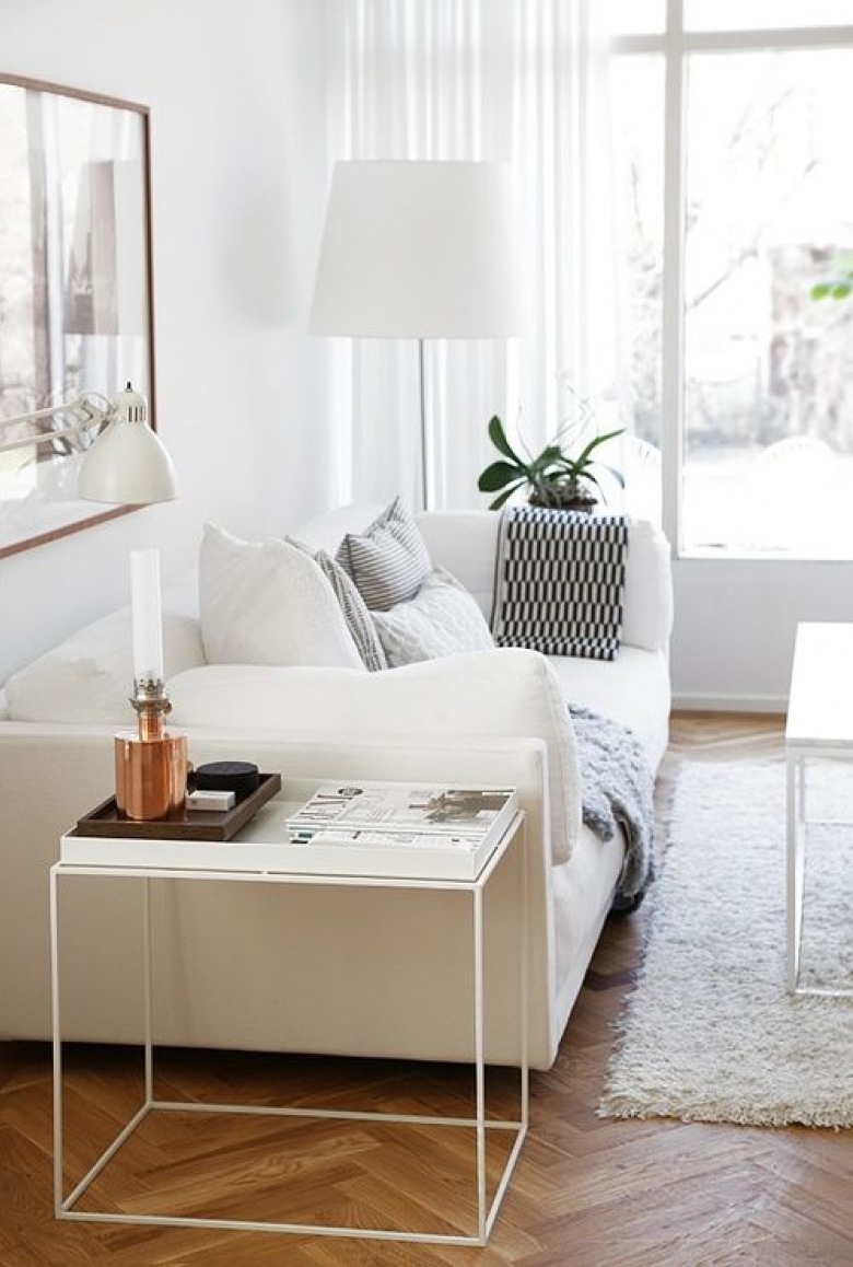 Biała sofa w salonie wygląda bardzo przyjemnie, choć zawsze warto urozmaicić ją dodatkami w bardziej wyrazistych kolorach. Podłoga w formie parkietu podkreśla za to naturalną stronę...