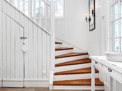 Biała konsolka z lustrem przy    drewnianych  schodach w domu (21960)