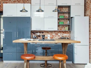 Biało-niebieska kuchnia nowoczesna z industrialnymi lampami,drewnianym stołem i ścianami z czerwonych cegieł (24072)