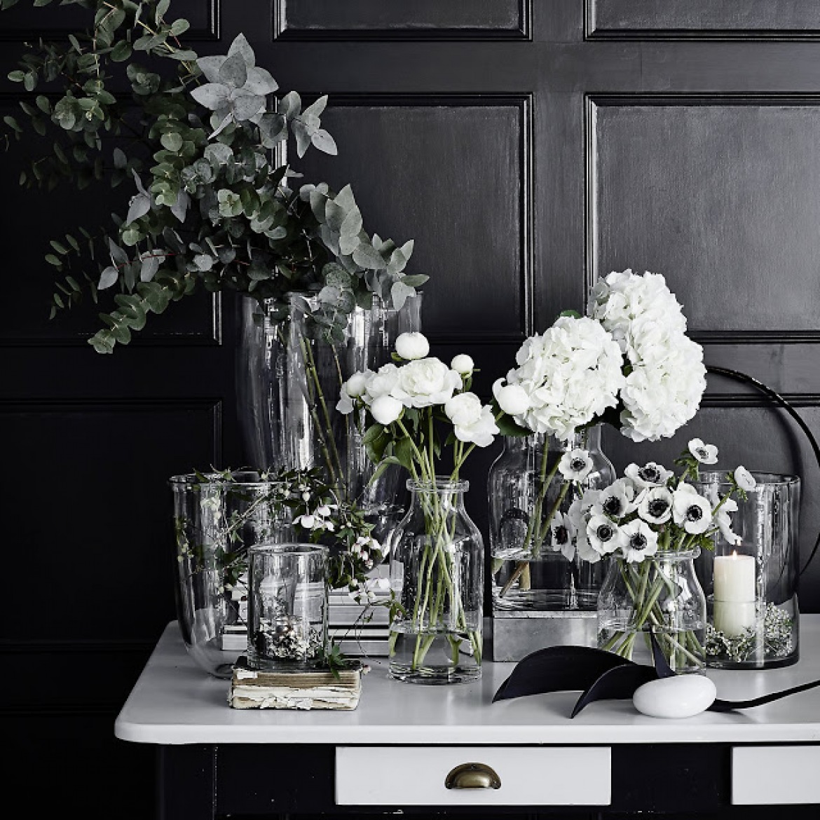 Szklane wazony i butelki z białymi kwiatami do kącika biurowego z czarnymi ścianami (47771)