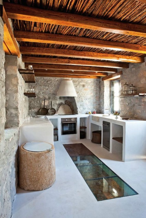 Oryginalna aranżacja kuchni w głównej mierze bazuje na kamieniach, którymi wyłożono ściany. Białe meble i jasna podłoga...