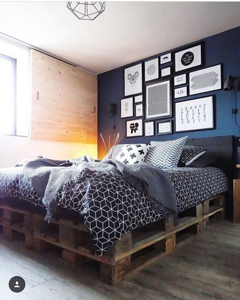 Oryginalna aranżacja sypialni opiera się na ciemnej palecie barw i elementach drewna. Na granatowej ścianie wisi bogata...