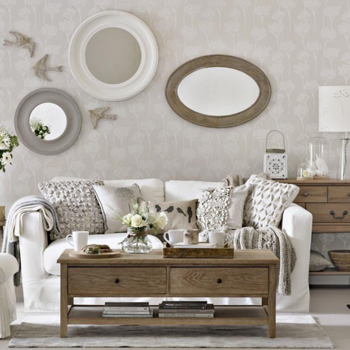 Szare i białe lustro okragłe,owalne lustro w drewnianej ramie,biała sofa,marokański lampion i tradycyjny drewniany stół ława z szufladami w salonie (26102)
