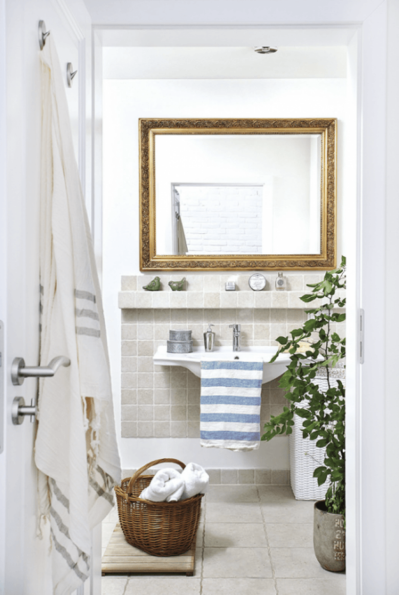 Biała łazienka z szarymi płytkami i ze stylowym rzeźbionym lustrem w złotych ramach (24839)