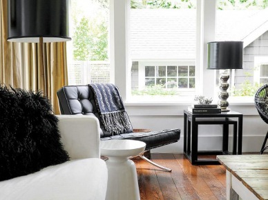 Srebrno-czarne lampy w stylu glamour,czarne pikowane fotele w stylu nowoczesnym,czarne kwadratowe stoliki pomocnicze,białty nowoczesny stołek i drewniane deski na podłodze (26784)
