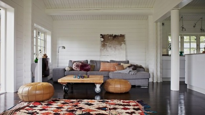 Tkane dywany berberyjskie w etnicznych wzorach,marokańskie skórzane pufy,stolik z palety na kółkach i szara sofa w salonie (24897)