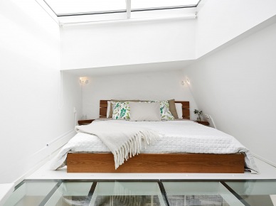 Drewniane łóżko w białej sypialni ze świetlikiem w suficie i przeszkloną podłogą (22892)