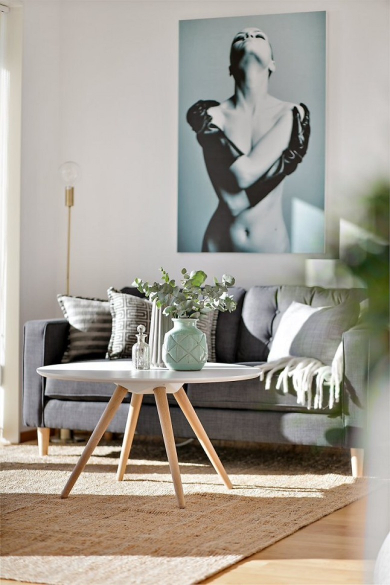 Duże fotografie na ścianie nad grafitową sofą,miętowe dodatki w aranżacji białego salonu z okragłym nowoczesnym stolikiem (28424)