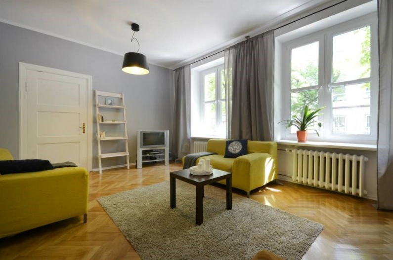 Bardzo duży i wysoki salon urządzono w prostym skandynawskim stylu. Wnętrze zdecydowanie dekorują żółte fotele, poza...