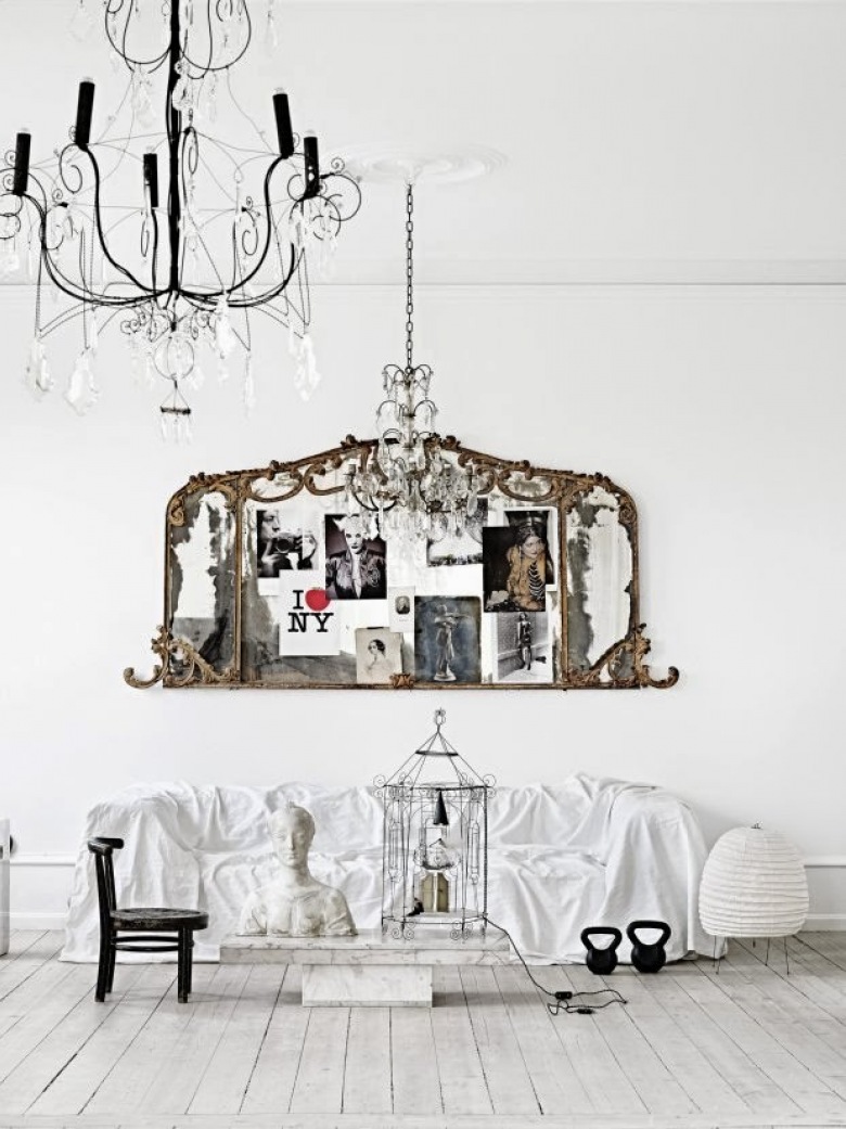 Francuskie rzeźbione ramki z fotografiami jako ozdoba na ścianie nad biała sofą i kutymi żyrandolami z kryształkami (24615)