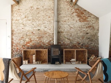 rustykalny salon, ale w nowoczesnym wydaniu - w tle ściana z czerwonej cegły,proste, drewniane meble oraz żeliwny, czarny kominek o prostej...