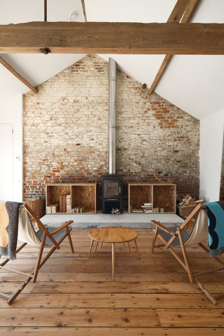 rustykalny salon, ale w nowoczesnym wydaniu - w tle ściana z czerwonej cegły,proste, drewniane meble oraz żeliwny,...