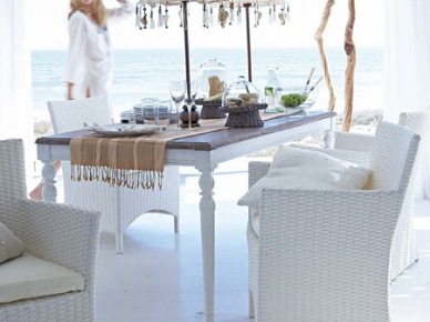 Letnia biała jadalnia na śródziemnomorskim tarasie z drewnianym stolem, wiklinowymi fotelami i parasolkami z wisiorkami (23927)