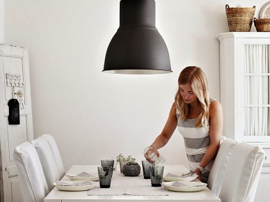 Biały stół, ubranka na krzesłach i duża industrialna czarna lampa w jadalni (22432)