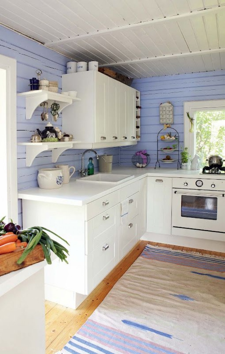 Małą kuchnię o tradycyjnym wyglądzie urozmaicono ścianą pomalowaną na niebieski odcień. Kolorowe deski przykuwają do...