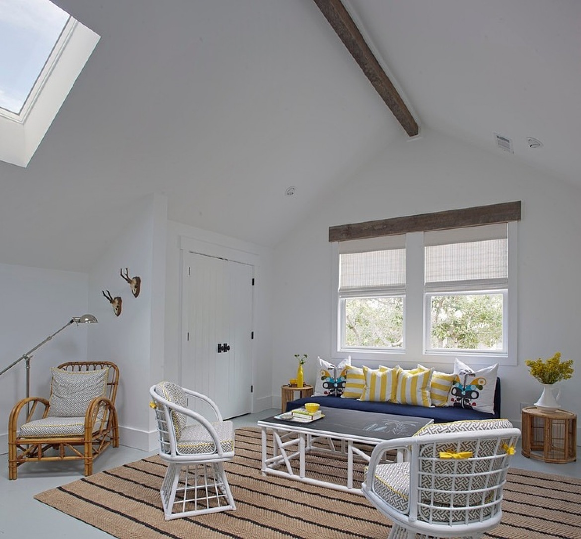 Białe meble z rattanu, beżowy dywan i żółto-niebieskie poduszki w aranżacji pokoju (23805)