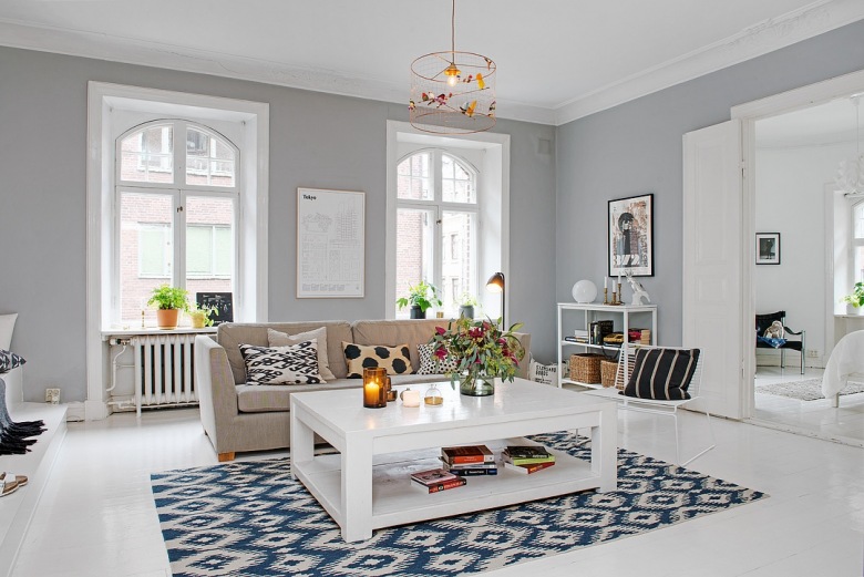 Biały stolik kawowy z półka,beżowa sofa,niebiesko-biały dywan i szare ściany w aranżacji salonu skandynawskiego (26985)